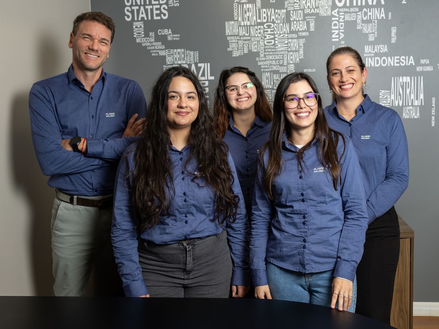 Equipe da Plan35 em frente ao painel com o mapa-múndi